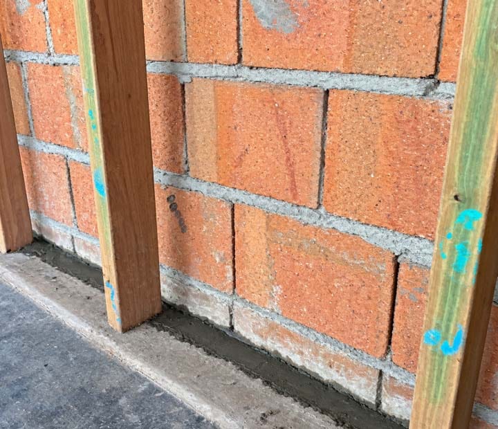 Efflorescence and moisture damage on the bottom courses of the rear brick wall, the white salty crust left behind by ground moisture, with fresh mortar packed into the wall to floor junction. Efflorescence and moisture damage on the bottom courses of the rear brick wall, the white salty crust left behind by ground moisture, with fresh mortar packed into the wall to floor junction.