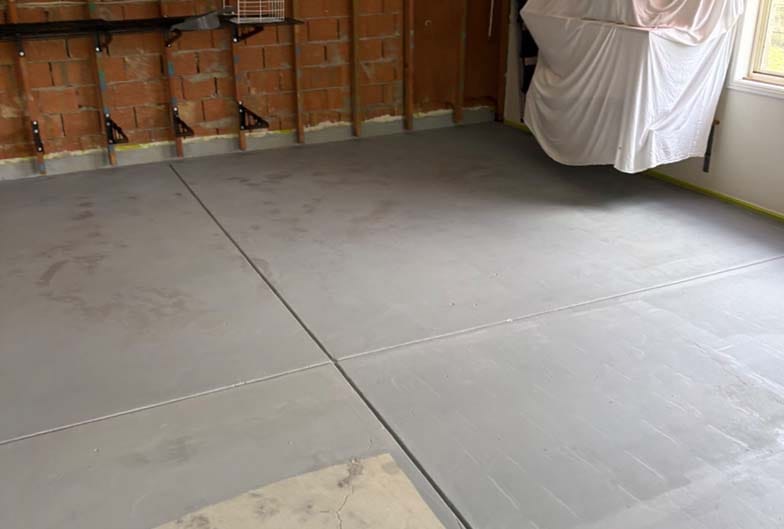 Most of the floor now coated, while the uncoated patch in the foreground reveals the raw, cracked concreteunderneath and the stripped rear brickwork with injection ports fitted